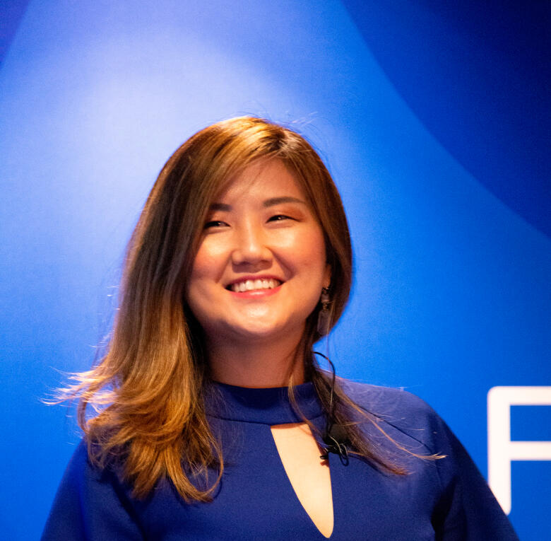 Qin - author and financial coach the profile photo of Qin in public speaking spot light